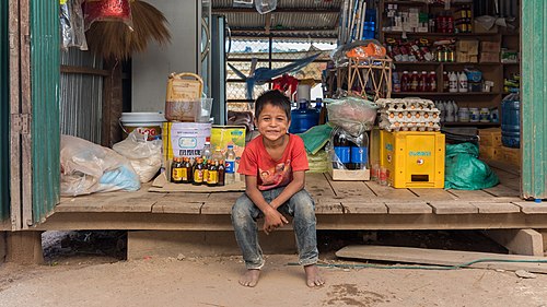 Young vendor smiling, sitting in a grocery store in Laos